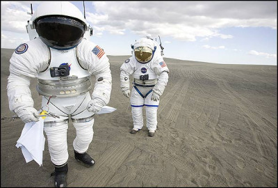 Vemos  a dos astronautas que tienen unos trajes espaciales  mas moderno en color blanco con cascos y guantes del mismo color